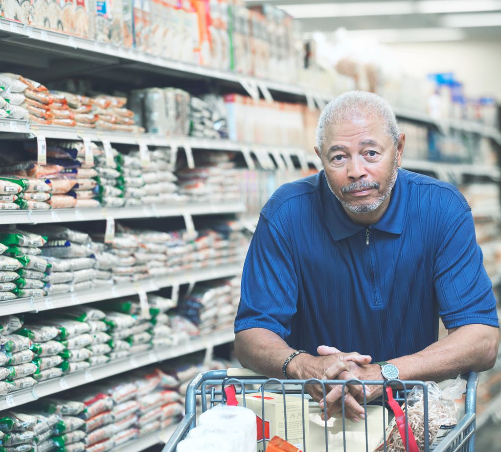 Man with lumbar spinal stenosis leaning on shopping cart