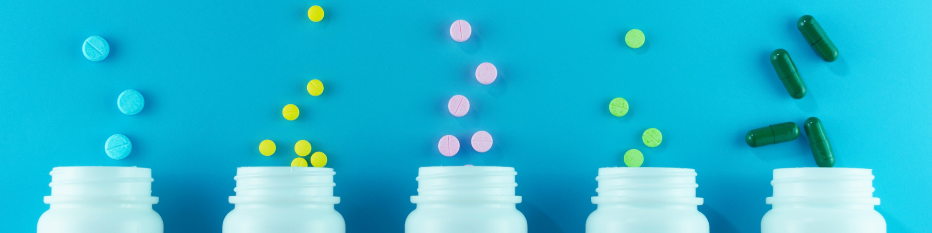 Various pill bottles lined up against a blue background.